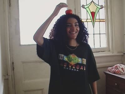 a woman holding an apple on her head in front of a window