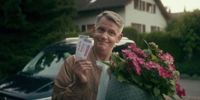 a man holding a piece of paper next to a car