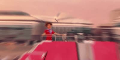 a blurry photo of a woman standing on a luggage cart