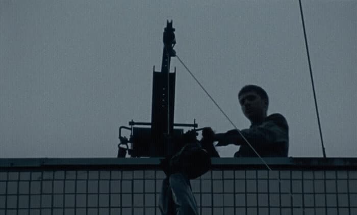 a man standing on top of a roof next to a power pole