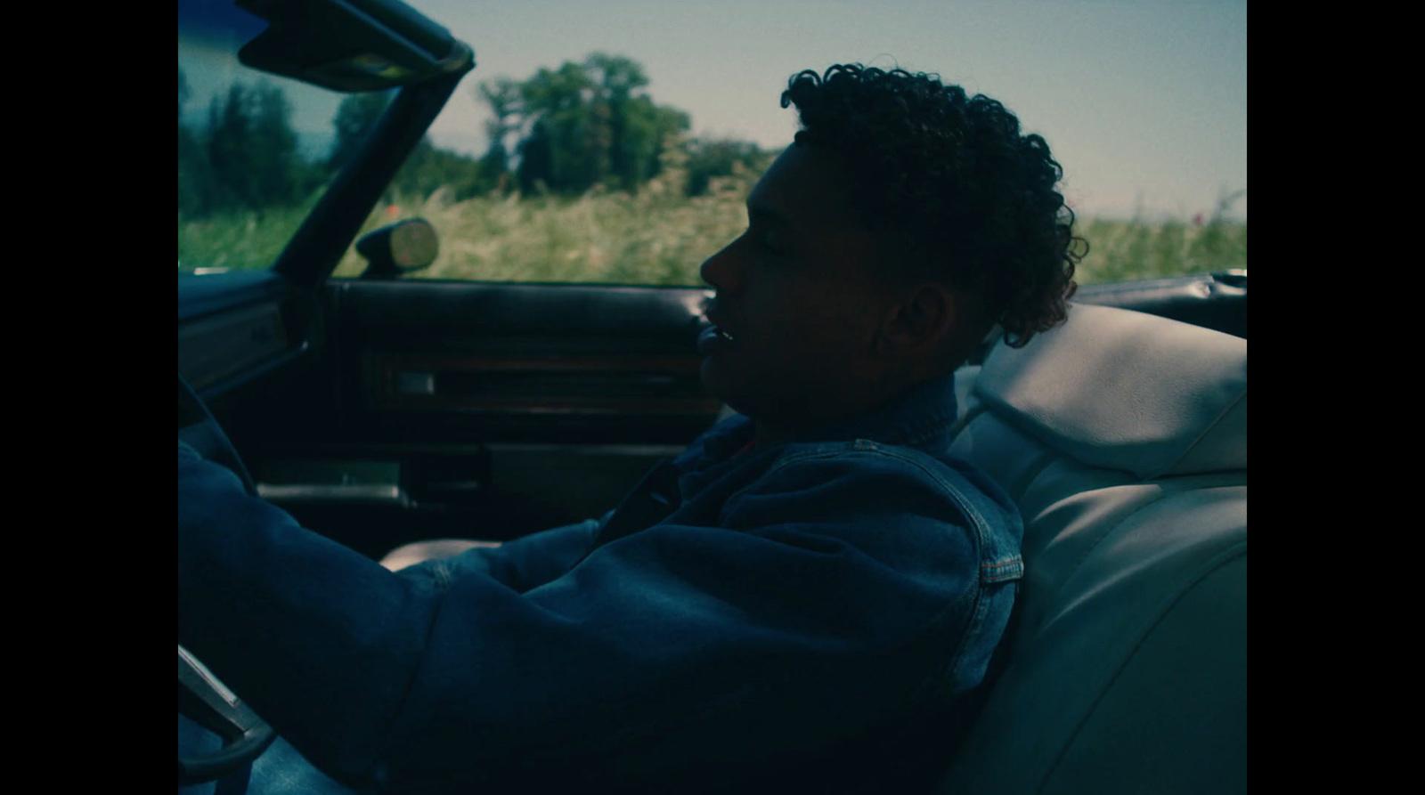 a man driving a car in a grassy field