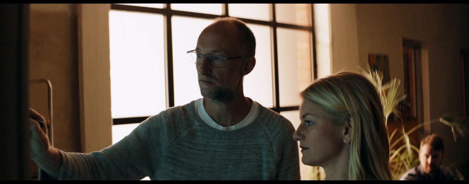 a man standing next to a woman in front of a window