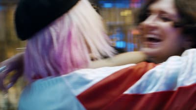a woman with pink hair is talking to another woman