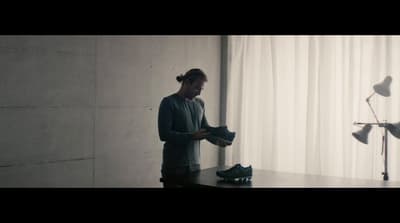 a man standing next to a table with a pair of shoes on it