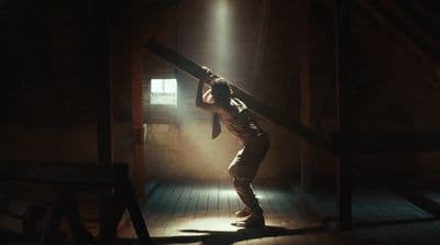 a man standing in a dark room holding onto a pole