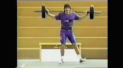 a man holding a barbell in a gym