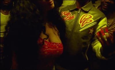 a woman in a red dress standing next to a man in a green jacket