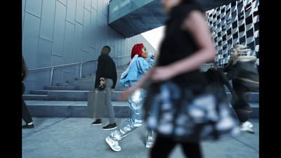 a group of people walking down a sidewalk next to a building