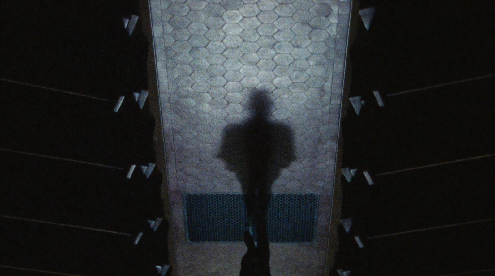 a shadow of a person standing in front of a urinal