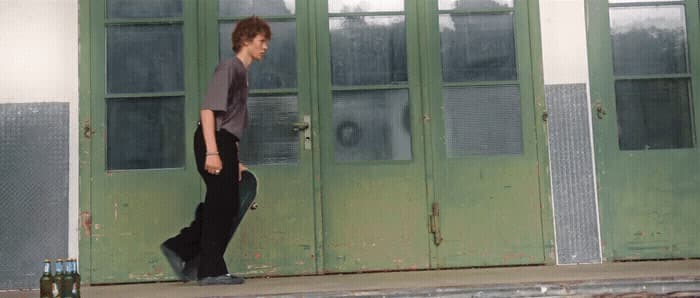 a young man is walking in front of a green door