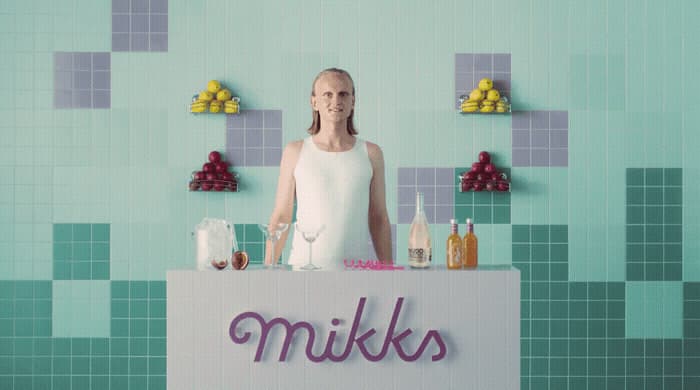 a woman standing behind a counter with bottles and glasses on it