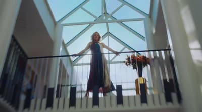 a woman in a long dress standing on a balcony