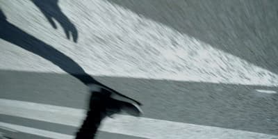 a man riding a skateboard down a street next to a wave
