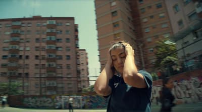 a woman covering her ears while walking down a street