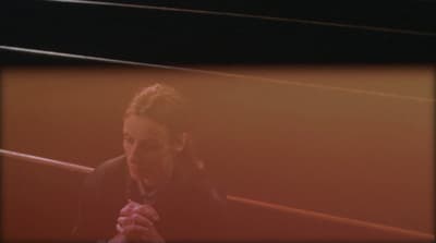 a woman in a black jacket is holding her hands together