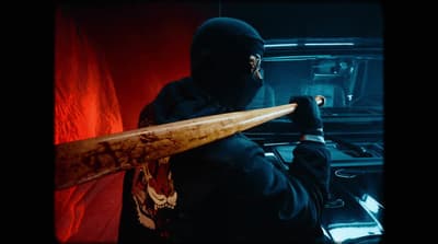 a man in a black mask holding a wooden stick