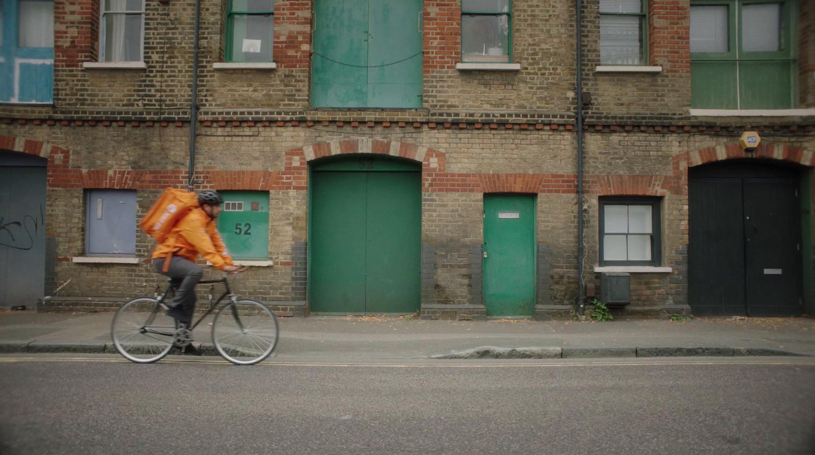 a man riding a bike down a street past a tall brick building