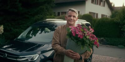 a man holding a bouquet of flowers next to a car