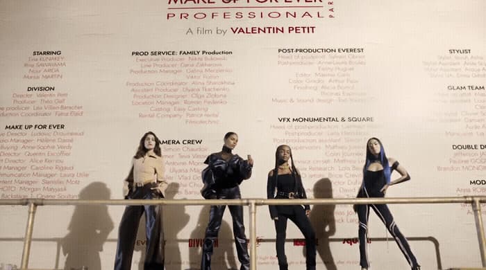 a group of women standing next to each other in front of a wall