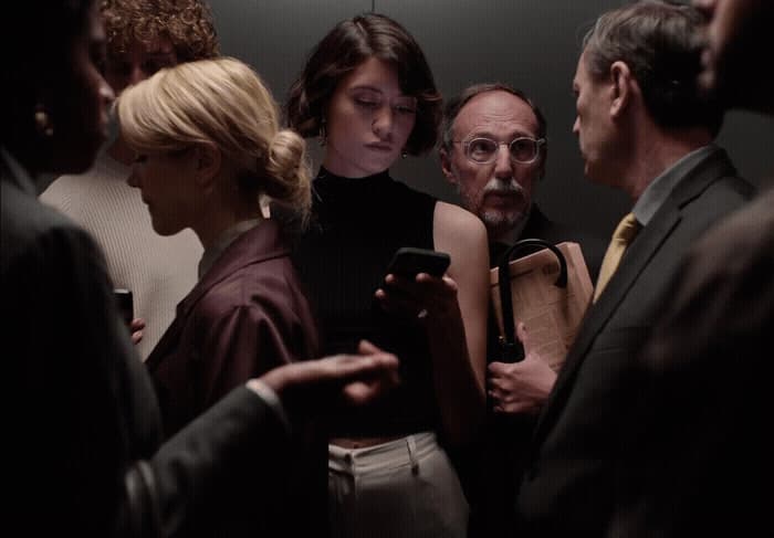 a group of people standing around each other looking at a cell phone