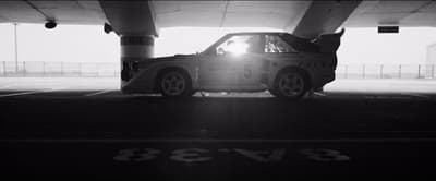 a car parked in a parking garage under a bridge