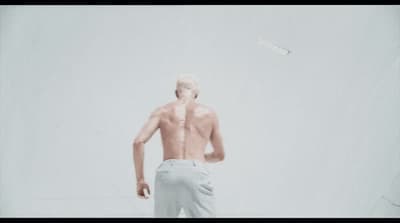 a man with no shirt is flying a kite