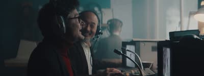a couple of men standing next to each other in front of a microphone