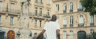 a man walking down a street past a tall building