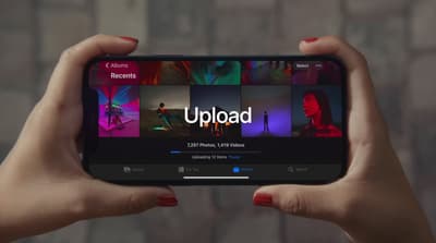 a person holding up a cell phone with the app upload on it
