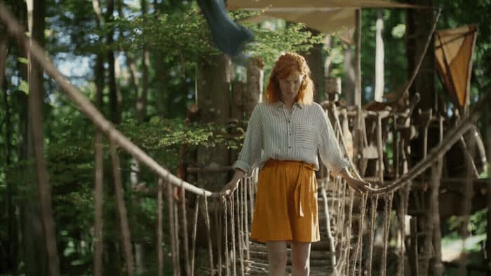 a woman is walking across a rope bridge