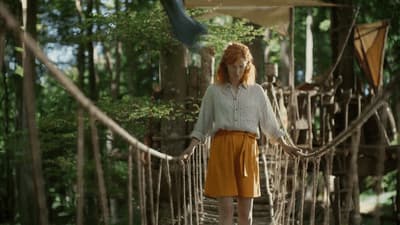 a woman is walking across a rope bridge