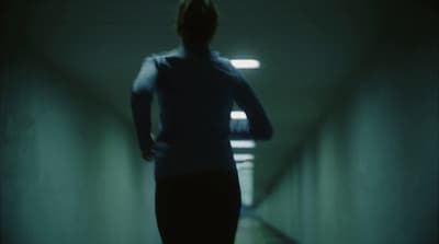 a woman is walking down a dark hallway