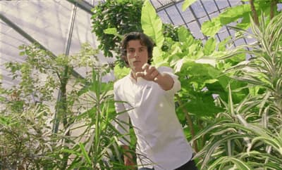a man pointing at the camera in a greenhouse