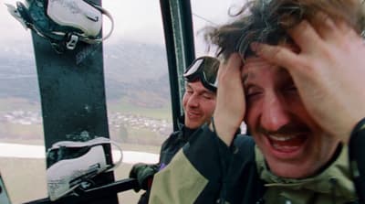 a man holding his head while riding a ski lift