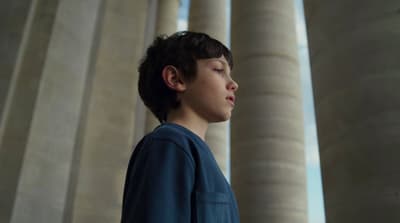a young boy standing in front of columns