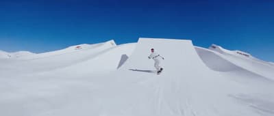 a man riding a snowboard down the side of a snow covered slope