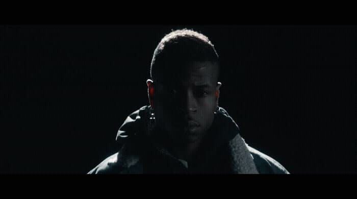 a man standing in the dark wearing a hoodie