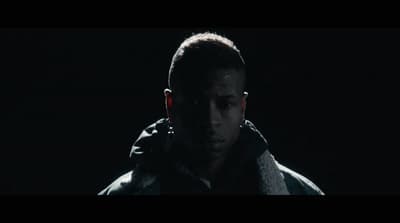a man standing in the dark wearing a hoodie