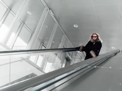 a woman riding an escalator down a metal handrail