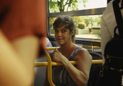 a woman sitting on a bus with her hand on the handle