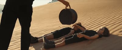 two people laying on the ground in the sand