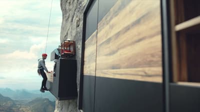 a man standing on top of a cliff next to a building