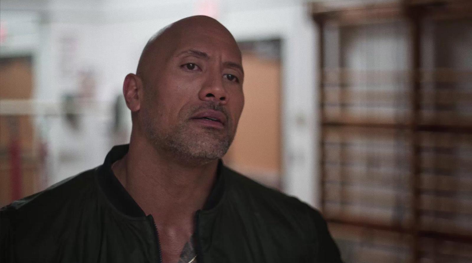 a bald man in a black jacket looking off into the distance