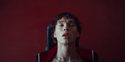 a man with his eyes closed wearing a necklace