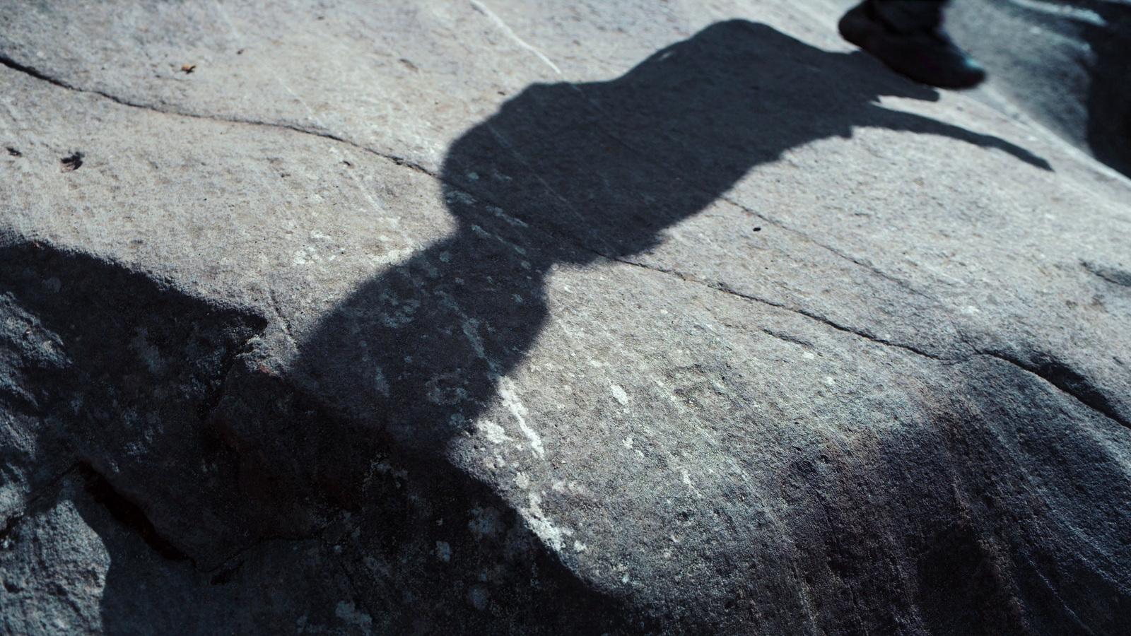 a shadow of a person standing on a rock
