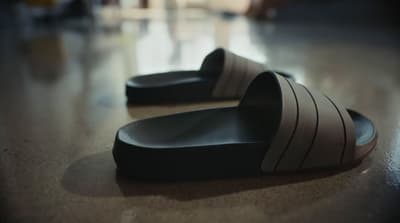 a pair of black and white slippers sitting on top of a wooden floor