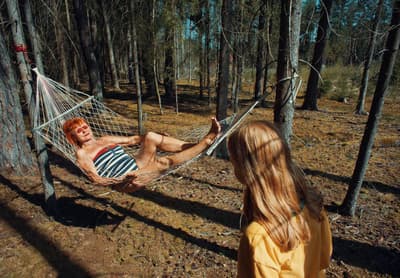 a man laying in a hammock in the woods
