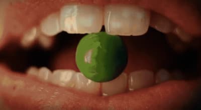 a close up of a person holding a green object in their mouth