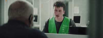 a man in a green vest talking to a man in a mirror