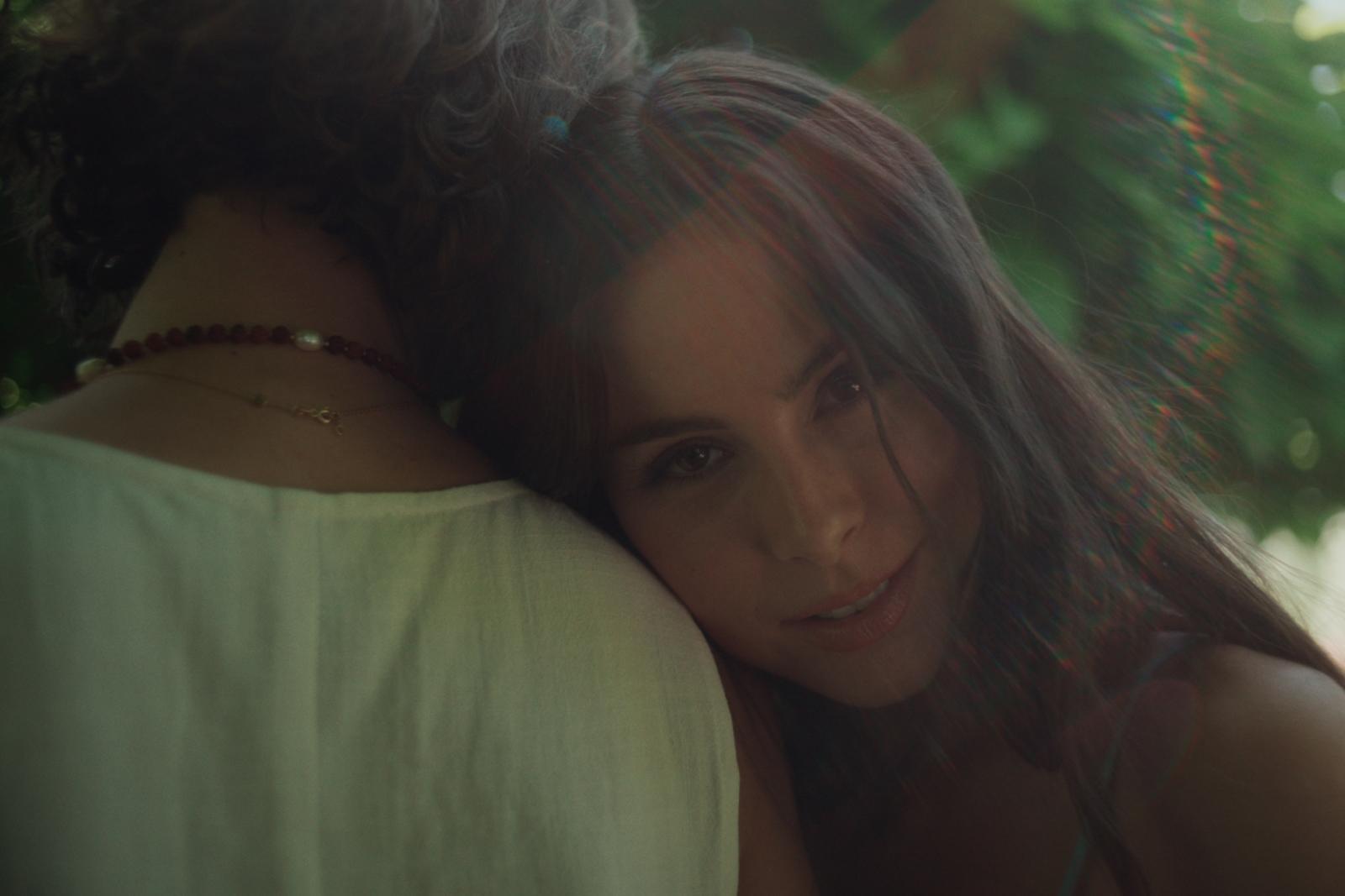 a woman with long hair hugging another woman